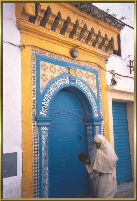 Verhllte Frau vor einem der prchtigen Hauseingnge in Essaouira
